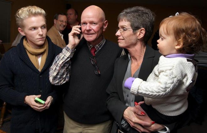 (John Clark/The Gazette)  N.C. House winner Dana Bumgardner talks on his cell phone as he celebrated his victory with his son Austin, left, his wife Cindy and their 15 month-old grandaughter Payton as they gathered with family and friends at the Villa Roma Restuarant in Gastonia Tuesday evening.