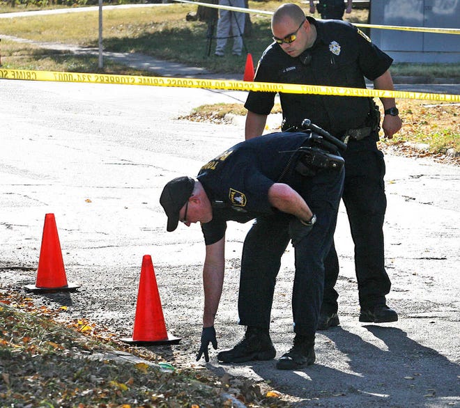 Police look for evidence in front of the residence at 629 S.E. Locust, where the shooting was reported to have originated.