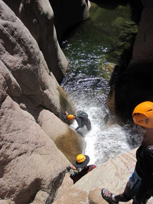 Hikers in wetsuits and helmets explore Salome Canyon's Salome Creek in Arizona's Tonto National Forest. The sport of canyoneering includes hiking, climbing, sliding and wetsuit-wading, but can be tackled by novices accompanied by an experienced guide.