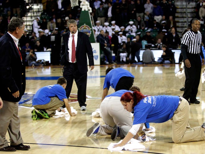 Workers wipe the floor during halftime of the Florida Gators versus Georgetown Hoyas game aboard the USS Bataan at Mayport Harbor on Friday in Jacksonville. The game was canceled at halftime because of condensation on the court causing slippery conditions.