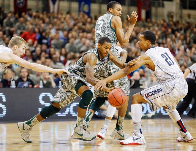 Michigan State guard Keith Appling, center, and Connecticut guard Omar Calhoun (21) vie for the ball during their NCAA men's basketball game on Saturday, Nov. 10, 2012, on the Ramstein U.S. Air Force Base, in Ramstein, Germany. (AP Photo/Michael Probst)