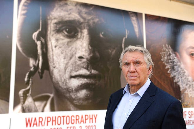 Photographer Don McCullin poses Tuesday in front of the Houston Museum of Fine Arts' sign promoting the new War/Photography exhibit in Houston. The exhibit displays the work of 280 photographers from 28 nations covering the Mexican-American War in 1846 to present-day. McCullin has four photos in the exhibit.