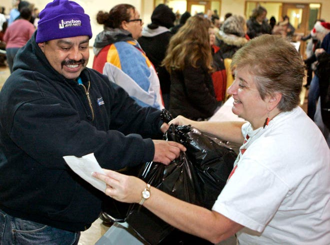 Carlos Espinoza of Belvidere receives a bag of toys from volunteer Shelly Cook Saturday, Dec. 10, 2011, during the Rockford Register Star Empty Stocking Giveaway at the Rockford Rescue Mission in Rockford.