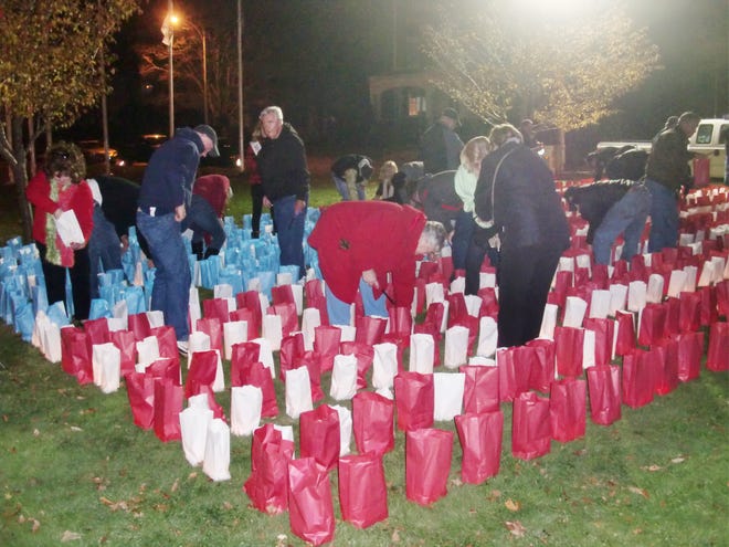 Volunteers light candles inside red, white and blue paper bags assembled in the from of an American flag as part of a luminary memorial organized by the Taunton Fire Department for Veterans Day. The luminary took place at Church Green in downtown Taunton on Sunday night.