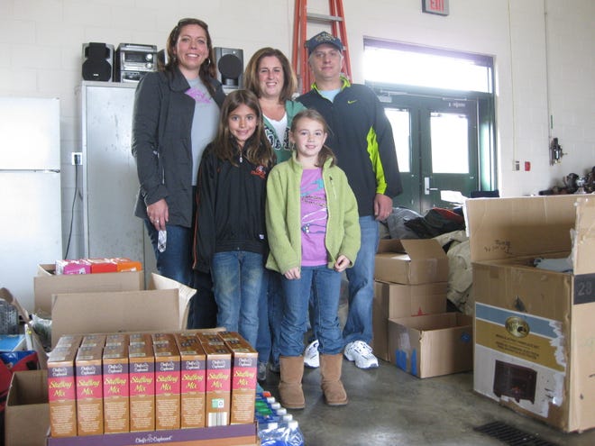 Ava Venturelli, 8, who asked for donations to Hurricane Sandy victims instead of birthday presents, poses with, back row from left, her mom, Cindy Venturelli, Leigh-Beth Clark, her dad, Tony Venturelli, and her friend Sarah Clark, 8, amid boxes of supplies at the Oakland Fire Station in Taunton on Sunday.