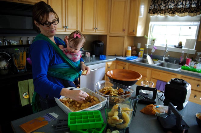 Shanna Watson peels apples while holding her daughter, Maya.