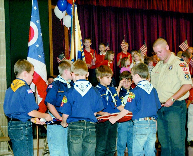Christina McCune snapped this photograph Friday during a Veterans Day celebration at St. Barbara Catholic School, 2809 Lincoln Way NW, in Massillon. During the celebration in the St. Barbara Parish Life Center, members of Cub Scouts Pack 925 fold the US flag. Jeff Ramsey (right) is the Cub Scout Master for Pack 925. Veterans and active military personnel were invited to the program and luncheon. The Cub Scouts presented the colors, folded and gave a flag to veteran Dr. Harold R. Walker. Students from Pre-K through eighth grade sang songs and read prayers. Student artwork decorated the walls, and veterans were invited to bring memorabilia to put on display. At the conclusion of the program, Municipal Court Judge Edward Elum accepted a $1,000 check donated by the St. Barbara community, which will buy one of the plaques on the Wall of Honor in downtown Massillon, paying tribute to 16 Stark Countians who were killed in Bosnia, Iraq and Afghanistan.