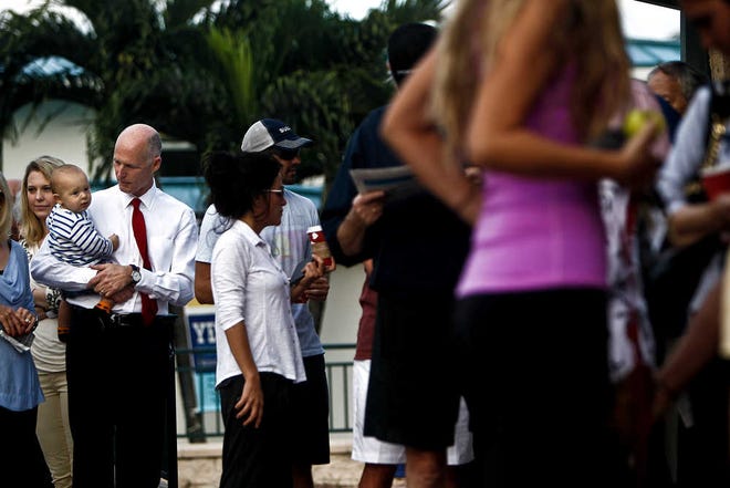 Gov. Rick Scott holds his grandson August Guimard as he and other voters wait in line to vote, at St. Ann's Catholic Church, Tuesday, Nov. 6, 2012, in Naples, Fla. (AP Photo/Naples Daily News, Scott McIntyre) FORT MYERS OUT