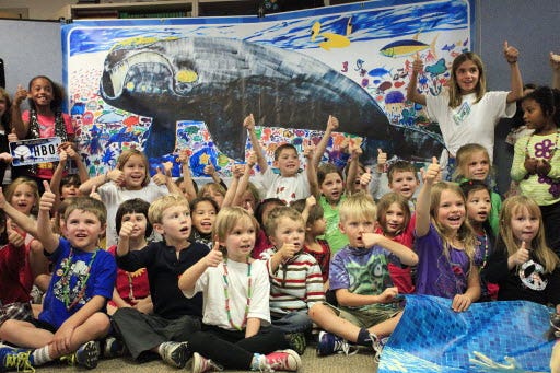 Students at the Millhopper Montessori School take a group photo near a painting after learning about the endangered North Atlantic right whale, Wednesday, November 14, 2012 in Gainesville, Fla.