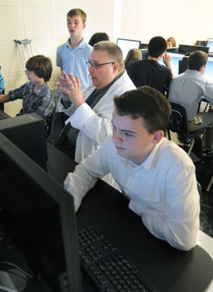 Eastampton Community School science teacher James MacCarthy, center, works with eighth grader Christopher Scoglio, standing behind Mr. MacCarthy, during the Gateway to Technology Class on Wednesday. In the foreground is student Thomas O'Brien. Lockheed Martin is sponsoring a first-time engineering curriculum at three middle schools and Eastampton is one of them. The other two are Mount Holly and Lumberton.