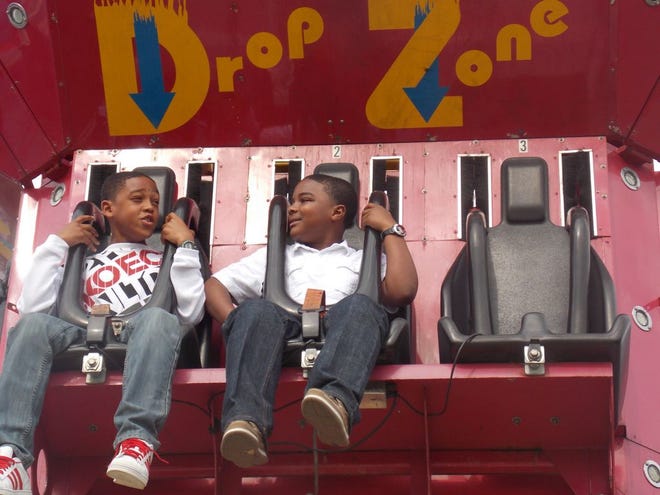 Two boys look at each other while being pulled to the to of the “Drop Zone” ride at the Sunshine Festival Sunday.