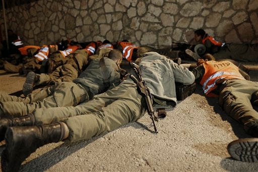 Israeli soldiers take cover as an air raid siren warns of incoming rockets before the funeral of Aaron Smadja, one of the three Israelis killed by a rocket fired from Gaza, at a cemetery in the southern town of Kiryat Malachi, Thursday, Nov. 15, 2012. (AP Photo / Tsafrir Abayov)