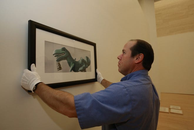 Paul Arthur, the chief prepartor, hangs one of the pieces of artwork for the “Sendak and Co.: Children’s Book Illustrations ‘Since Where The Wild Things Are’ ” exhibit at the Appleton Museum of Art last week.