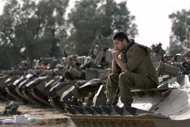 Israeli soldiers with armored vehicles gather in a staging ground near the border with Gaza Strip, southern Israel, Friday, Nov. 16, 2012. Fierce clashes between Israeli forces and Gaza militants are continuing for the third day.(AP Photo/Tsafrir Abayov)