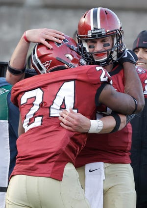 Harvard quarterback Colton Chapple congratulates teammate Treavor Scales (24) after Scales scored a touchdown late in the fourth quarter during the Crimson's victory over Yale on Saturday.
