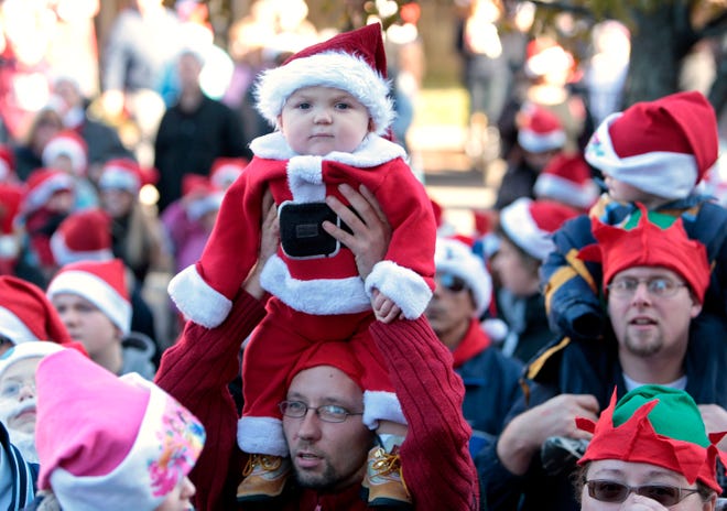 A baby Santa is lifted above the crowd of hundreds of people gathered on Main Street in Brockton on Sunday for the annual Santa Hat Challenge.