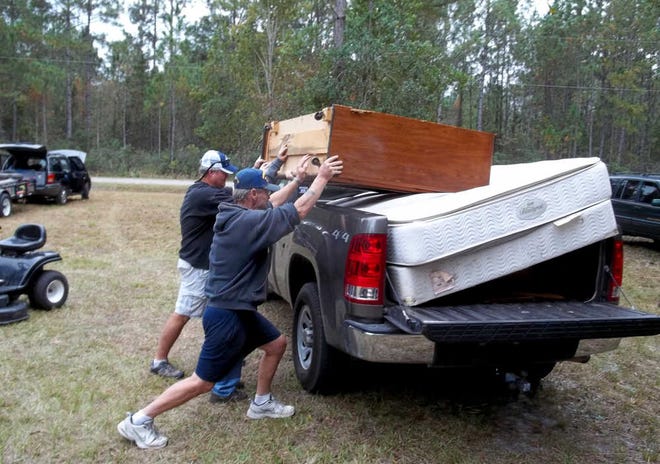 Ronald Mattice (foreground) loads ruined furniture into a truck to be hauled to the county landfill with the help of Randy Donaldson and his son, Cody Donaldson. Mattice and his wife, Sheila McCarthy, returned home on Nov. 3 to find the back windows of their home broken out by vandals, with black mold growing inside, ruined furniture and rain-damaged walls and floors. Most of their belongings were either gone or destroyed. The furniture had been urinated and defecated on. By DOUGLAS JORDAN, Special to The Record
