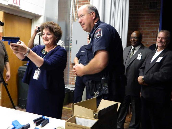 Julie Ford, Topeka USD 501 superintendent, takes a practice shot with the direction of officer Daren Davies, of Topeka Public Schools Police, on Monday at what was formerly Avondale East.