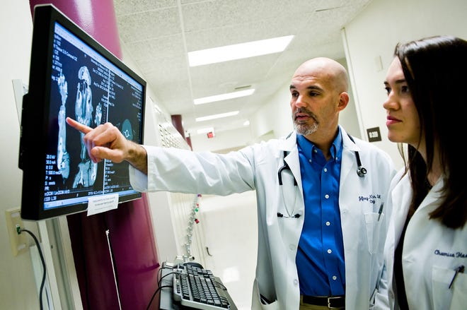 Jeff Bryan, left, head of oncology at the University of Missouri College of Veterinary Medicine Veterinary Medical Teaching Hospital, looks over a CT scan of a dog with cancer Monday with veterinary oncology resident Chamisa Herrera at the teaching hospital. Bryan is seeking dogs to participate in a study that uses bacteria to battle cancer.