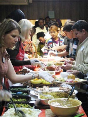 Catholic Charities staff and volunteers explain the variety of food in a traditional Thanksgiving meal as they serve refugees from six countries Tuesday in Jacksonville.