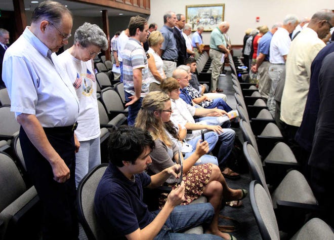 FILE - This June 20, 2012 file photo shows protesters remaining seated during an opening prayer during Hamilton County Commission meeting in Chattanooga, Tenn. It happens every week at meetings in towns, counties and cities nationwide. A lawmaker or religious leader leads a prayer before officials begin the business of zoning changes, contract approvals and trash pickup. But citizens are increasingly taking issue with these prayers, some of which have been in place for decades. At least five lawsuits around the country - in California, Florida, Missouri, New York, and Tennessee - are actively challenging pre-meeting prayers. (AP Photo/Chattanooga Times Free Press, Dan Henry, File)