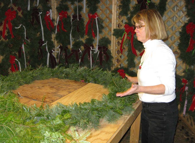 Marlene Ewing works on a wreath Friday at Country Christmas Trees. The tree farm is open Saturdays and Sundays. Intense watering helped the trees survive the drought.