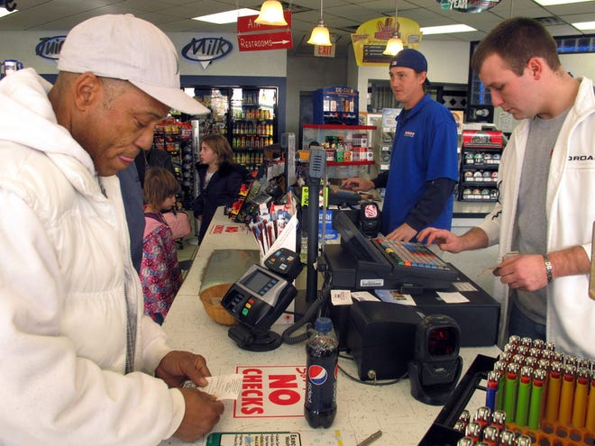Michael Arrington, left, buys a Powerball ticket from cashier Lee Heilig, right, on Friday, Nov. 23, 2012, at a DeliMart convenience store in Iowa City, Iowa. The jackpot had reached $325 million as of Friday. (AP Photo/Grant Schulte)