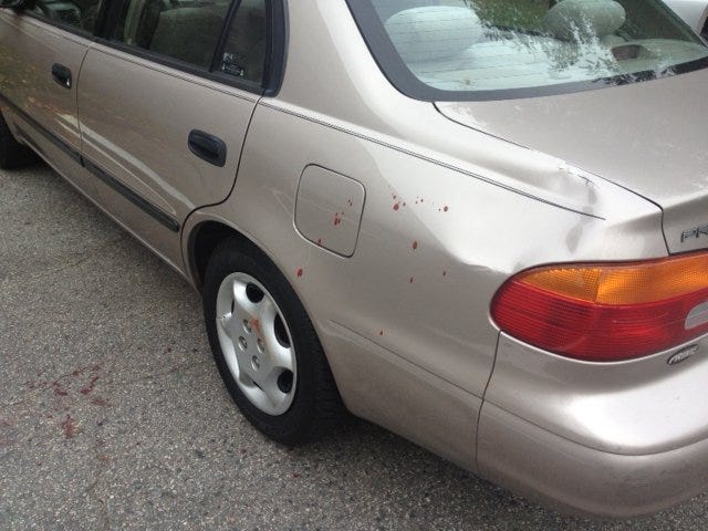 Scene of the stabbing early Saturday at 30 Queen Anne's Gate in Weymouth. Blood spattered on a car in the parking lot.