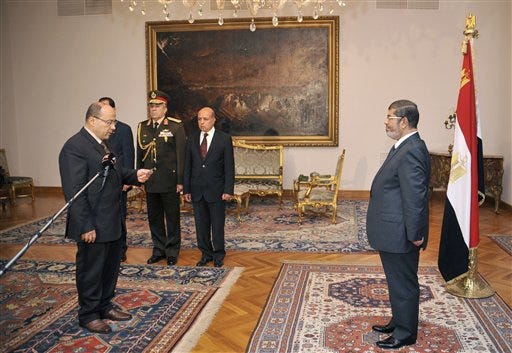 In this photo released by the Egyptian Presidency, President Mohammed Morsi, right, swears in his new Prosecutor General, Talaat Abdullah, left, in Cairo, Egypt, Thursday, Nov. 22, 2012. Egypt's president on Thursday issued constitutional amendments granting himself far-reaching powers and ordering the retrial of leaders of Hosni Mubarak's regime for the killing of protesters in last year's uprising. Morsi also on Thursday fired the country's top prosecutor by decreeing with immediate effect that he could only stay in office for four years and replacing him with Talaat Abdullah. Morsi fired Abdel-Maguid Mahmoud for the first time in October, but had to rescind his decision when he found that the powers of his office do not empower him to do so. (AP Photo/Egyptian Presidency)