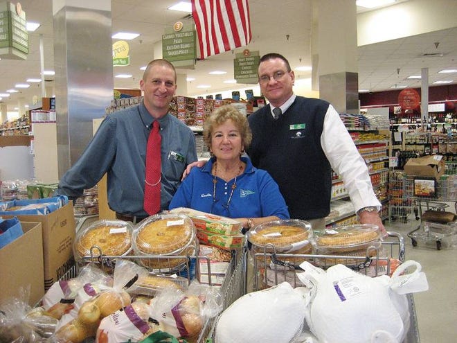 Anchor Boat Club event organizer Linda Cohen, center, stands with Publix assistant manager Jeff Keener, left, and manager Penn Walker, right, behind some of the food items that were distributed to families in need in advance of Thanksgiving.