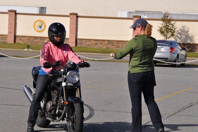 Motorcycle Safety Instructor Kristen Montejo of Cape Fox Professional Services, demonstrates proper body positioning to student AOAN(AW) Kandice Harrison of HS-11 during a motorcycle braking exercise during an all-female Basic Rider Course at NAS Jax on Nov. 20.