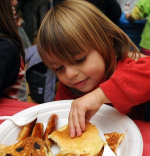 Kai Vickers-Richard, 2, of Natick, digs into a plate of pancakes and sausage at Johnson School's Pancake Party to help raise money for Monmouth Beach Elementary School, in Monmouth, N.J on Wednesday evening.
