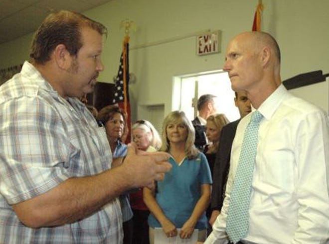 Chris Millender, left, vice president of the Franklin County Seafood Workers Association, talks with Gov. Rick Scott in Eastpoint during a meeting in October.