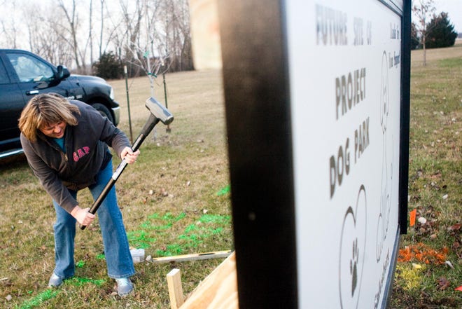 Melissa Powell of Galesburg pounds a sledgehammer into a wooden stake to help Tony Calek install a sign announcing the incoming dog park Thursday at Inbinder Park in Galesburg.