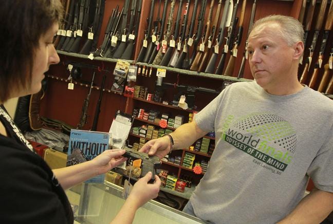 (Photo by Mike Hensdill/The Gaston Gazette) Troy Messick shows a 9mm handgun to Juli Rush Monday afternoon, December 3, 2012, at Bobby's Pawn on West Franklin Boulevard.