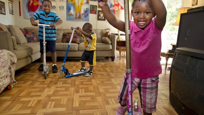 Virgil “Petey? Crawford, 8; Michael Foster, 2; and Makhia Foster, 2, play with scooters in the living room of their mobile home. They are being raised by grandmother Ethel Wright.