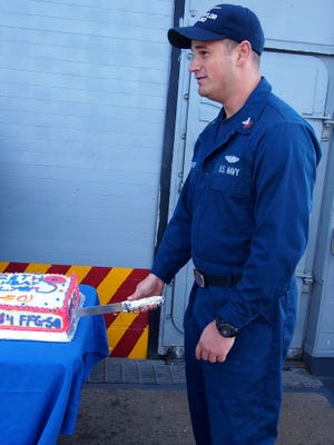 Electronics Technician Second Class Petty Officer George P. Murphy cuts cake bearing the guided missile frigate's name for her 28th birthday celebration.