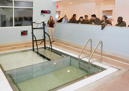 Liz Orr, physical therapist and swim coach at the Warrior Hope and Care Center aboard Camp Lejeune, explains the HydroPool during the center’s open house Friday afternoon. The pool is wheel chair accessible. While one side of the pool is three-feet deep the other side has a movable floor that can be lowered to a depth of eight feet if needed for deeper water therapy.
