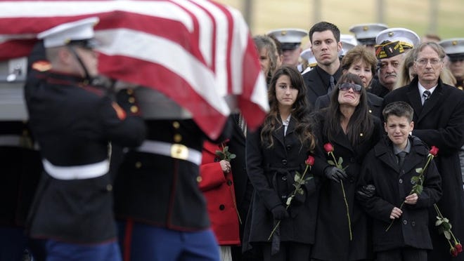 Catherine Stouffer — flanked by her children, Shannon, 17, and Shane, 12 — watches as the casket of her husband, Marine Chief Warrant Officer 3 Gary L. Stouffer of Hubert, N.C., is carried to the burial site Friday at Arlington National Cemetery in Arlington, Va. Stouffer, 37, was among four veterans killed when the parade float on which they were riding was hit by a train in Midland on Nov. 15. Susan Walsh/Associated Press