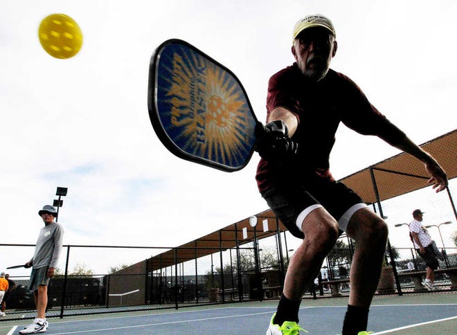 In this Monday, Dec. 3, 2012 photo, David Bone competes in a game of pickleball at Sun City West senior community in Surprise, Ariz. A hybrid of tennis, badminton and table tennis, pickleball is played on a court a quarter the size of a tennis court, with hard rackets and a variety of whiffle ball. The USAPA estimates now there are 100,000 to 150,000 pickleball players in the United States, and pickleball associations have started up in places like India and China. (AP Photo/Matt York)