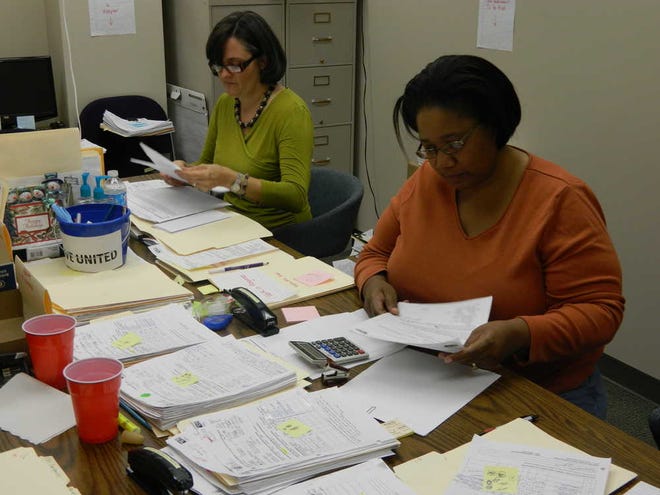 United Way volunteers Milly Echeverria and Shavonne Holmes work Friday to match families with people who want to buy them presents for this year's Adopt a Family program. As of Friday, more than 400 families still needed to be adopted.