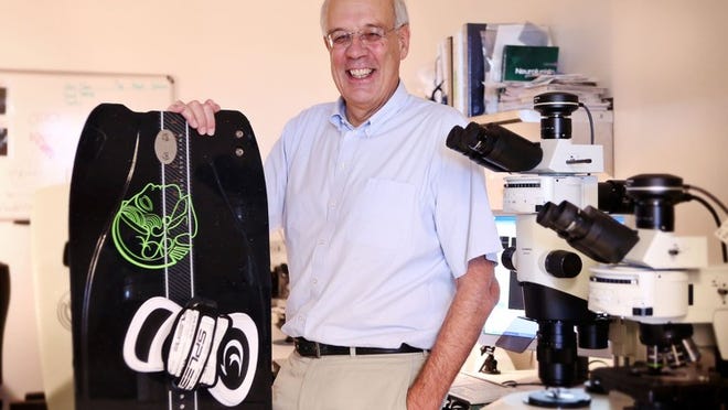 Nobel Prize-winning researcher Dr. Bert Sakmann holding his kiteboard with a Max Planck logo in his lab in Jupiter. Sakmann learned how to kiteboard in Palm Beach County while getting Max Planck here.