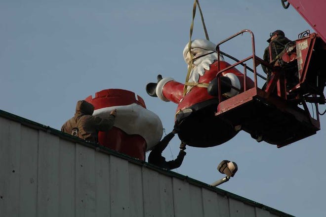 Workers place the top portion of the Brookwood Shopping Center Santa Claus on the bottom portion before the center's holiday open house. The 15-foot-tall Santa has been a staple of the Topeka community since 1963.