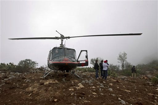 A rescue helicopter with members of the Mexican General Civil Aeronautic Directorate (DGAC) stand on top of the hill right next to the canyon where U.S.-born singer Jenni Rivera's jet crashed near the town of Iturbude, Mexico, Dec. 10, 2012. Rivera's life was cut short at its peak on Sunday by an airplane crash in northern Mexico that also killed six friends and co-workers.