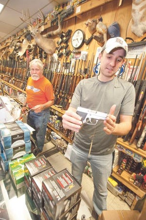 Dan Barth of Pekin Gun and Sporting Goods shows a Kahr 9mm concealable handgun as Craig Salmon looks on Tuesday evening. Barth described the brisk business in the store as normal for a weekday. In a major victory for gun rights advocates, a federal appeals court on Tuesday struck down a ban on carrying concealed weapons in Illinois — the only remaining state where carrying concealed weapons is entirely illegal — and gave lawmakers 180 days to write a law that legalizes it.