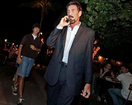 Anti-virus software founder John McAfee talks on his mobile phone as he walks on Ocean Drive in the South Beach area of Miami Beach, Fla., on his way to dinner Wednesday, Dec 12, 2012. McAfee arrived in the U.S. on Wednesday night after being deported from Guatemala, where he had sought refuge to evade police questioning in the killing of a man in neighboring Belize.