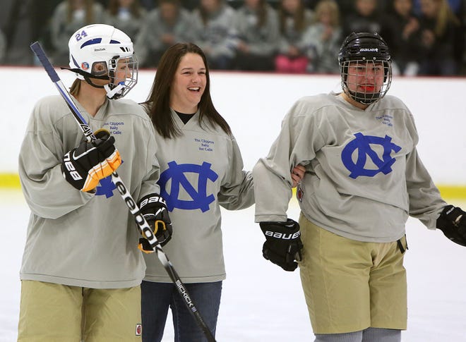 Rachael Cronk, mother of 5-year-old cancer patient Caroline "Calle" Cronk, is escorted onto the ice by Norwell's Kassidy Nadeau, left, and Tori Dinger during a high school hockey game and fundraiser for Calle, Wednesday, Dec. 12, 2012, at The Bog in Kingston. Rachael Cronk dropped the ceremonial first puck in both the Norwell girls and boys hockey games.
