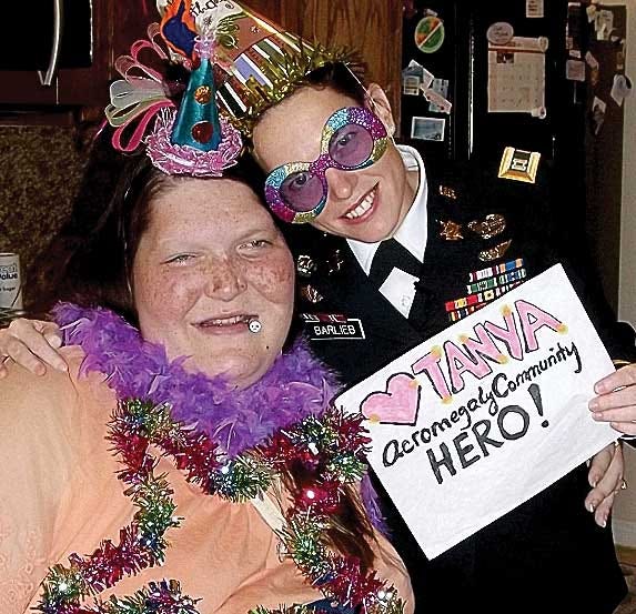Capt. Anne Barlieb, right, 5th Military Information Support Battalion holds a sign describing Tanya Angus, left, as an acromegaly hero. Both women have been diagnosed with the condition also known as gigantism for the overproduction of growth hormone by the pituitary gland. On Nov. 27, Barlieb delivered more than 200 postcards and cards from Fort Bragg Soldiers and Family members to Tanya as a show of support.