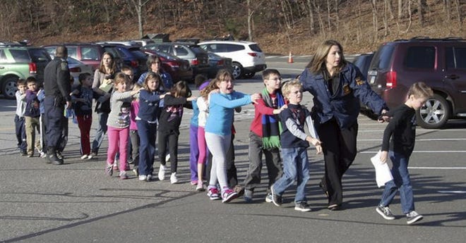 In this photo provided by the Newtown Bee, Connecticut State Police lead children from the Sandy Hook Elementary School in Newtown, Conn., following a reported shooting there Friday, Dec. 14, 2012.