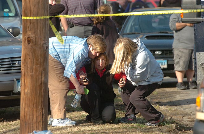 People are comforted near Sandy Hook Elementary School, Friday, Dec. 14, 2012 in Newtown, Conn. A man killed his mother at home and then opened fire Friday inside the elementary school where she taught, massacring 26 people, including 20 children, as youngsters cowered in fear to the sound of gunshots echoing through the building and screams coming over the intercom. (AP Photo/The Hour, Alex von Kleydorff)